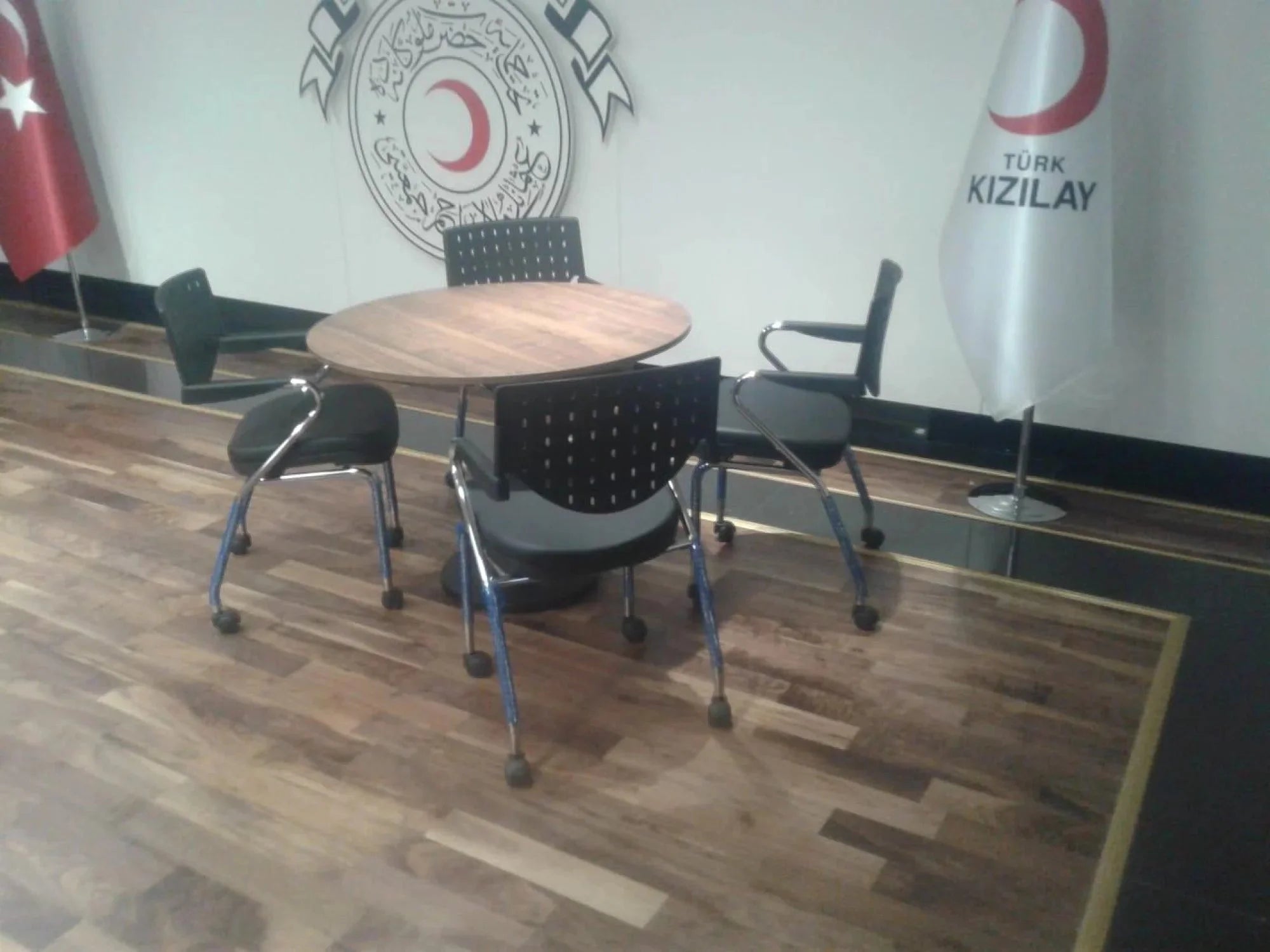 İstanbul Ofis Mobilya ahşap yüzeyli, metal ayaklı modern yuvarlak toplantı masası ve siyah ofis sandalyeleri