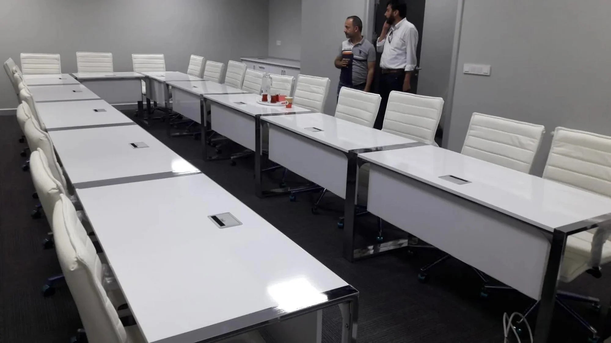 İstanbul Ofis Mobilya marka beyaz, modern tasarımlı, metal ayaklı, uzun toplantı masası ve beyaz ofis sandalyeleri.